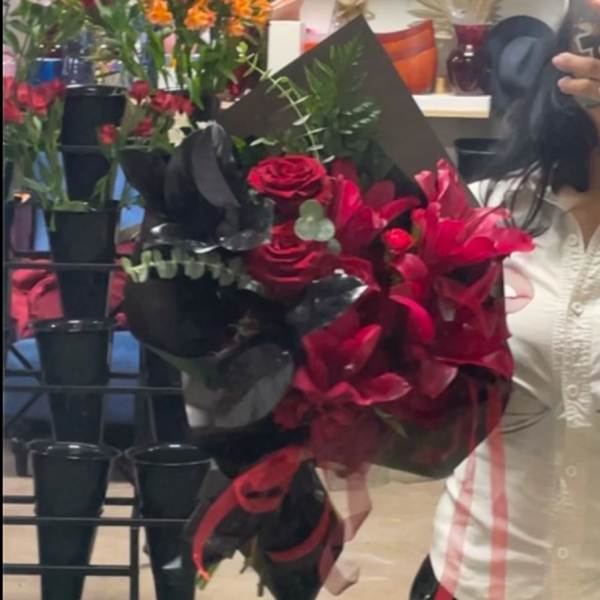 Bouquet of red roses and pink lilies wrapped in black paper