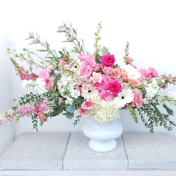 Large pink and white floral arrangement in a white vase