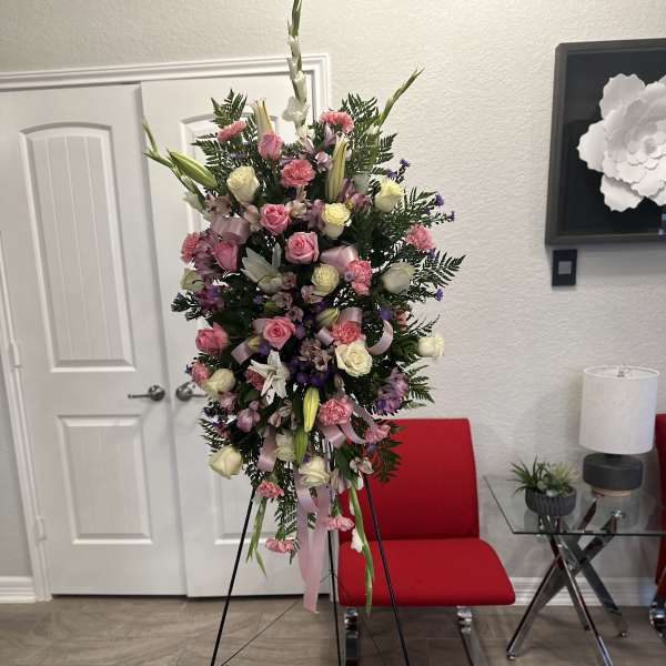 Tall pink and white standing spray of roses, lilies, and carnations on a metal easel