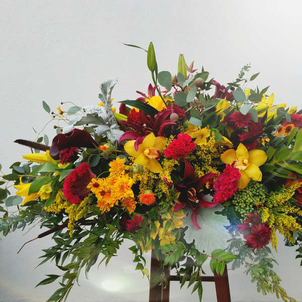 Large colorful floral arrangement with yellow, red, and burgundy blooms