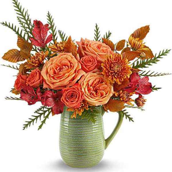 Peach roses and orange chrysanthemums in a green ceramic pitcher