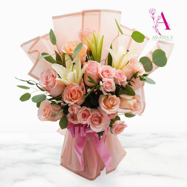Peach roses and white lilies in pink wrapping with a ribbon