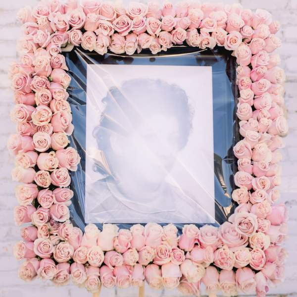 Square floral frame of pale pink roses around a portrait on an easel