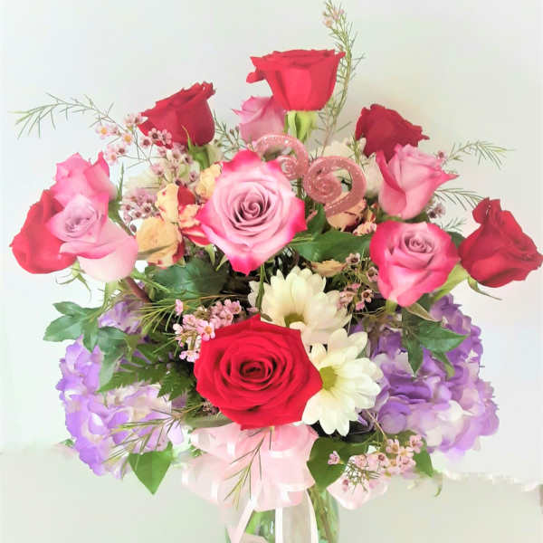 Bouquet of red and pink roses with purple flowers in a glass vase