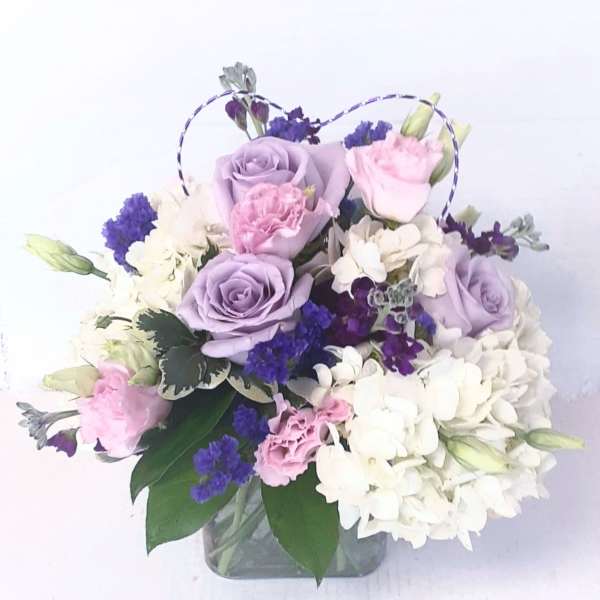 Lavender and pink roses with white hydrangeas in a glass vase