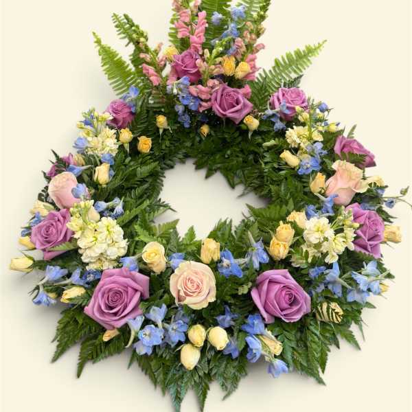 Circular floral wreath with purple and pink roses and blue flowers
