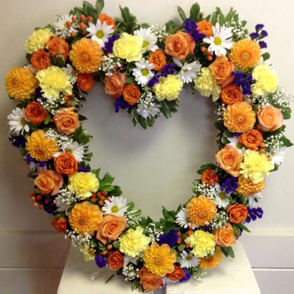 Heart-shaped floral wreath with orange, yellow, white, and purple flowers