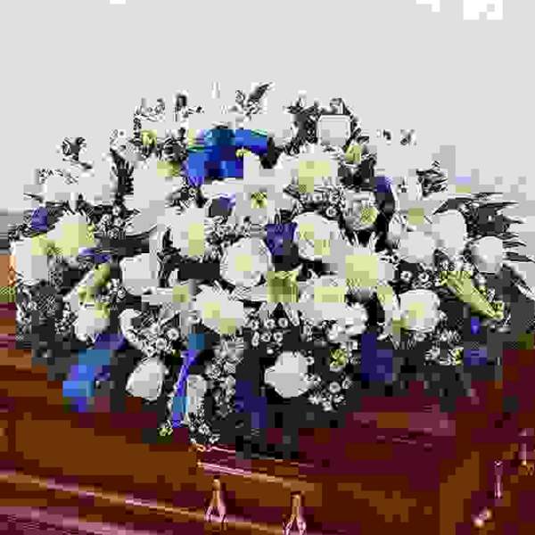 White floral arrangement with blue and yellow accents in a vase