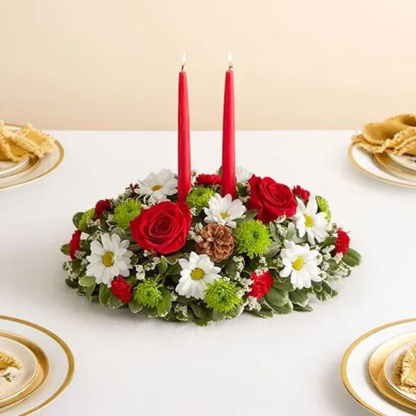 Red candles in a low floral centerpiece with white daisies and red roses