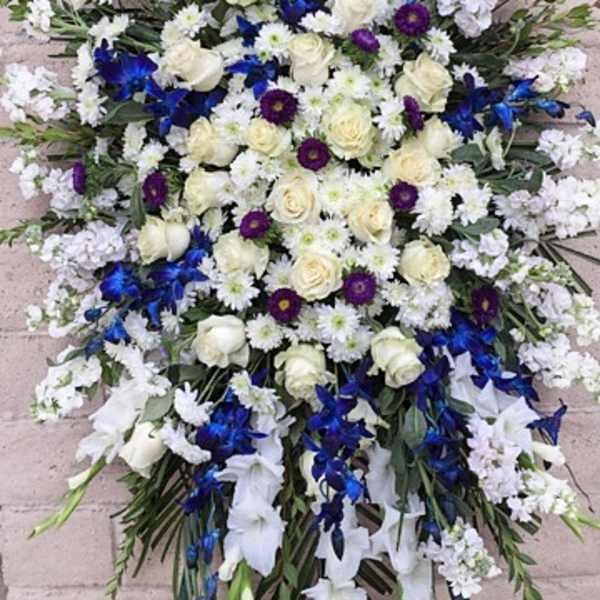 Large white and blue funeral spray on a stand