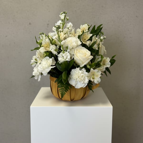 White floral arrangement in a wooden bowl on a pedestal