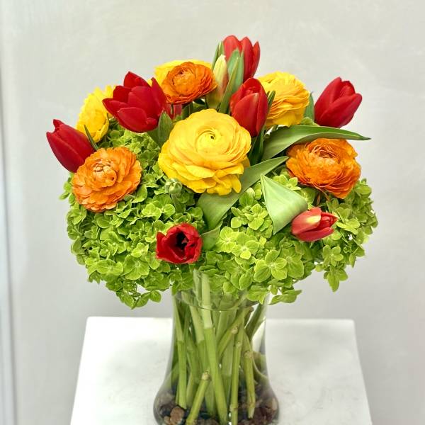 Bouquet of red, yellow, and orange flowers in a clear glass vase