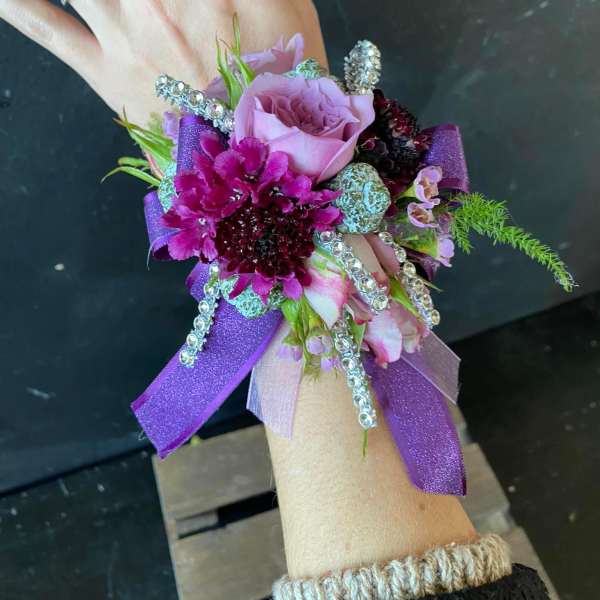Purple and pink wrist corsage with ribbon and rhinestone accents