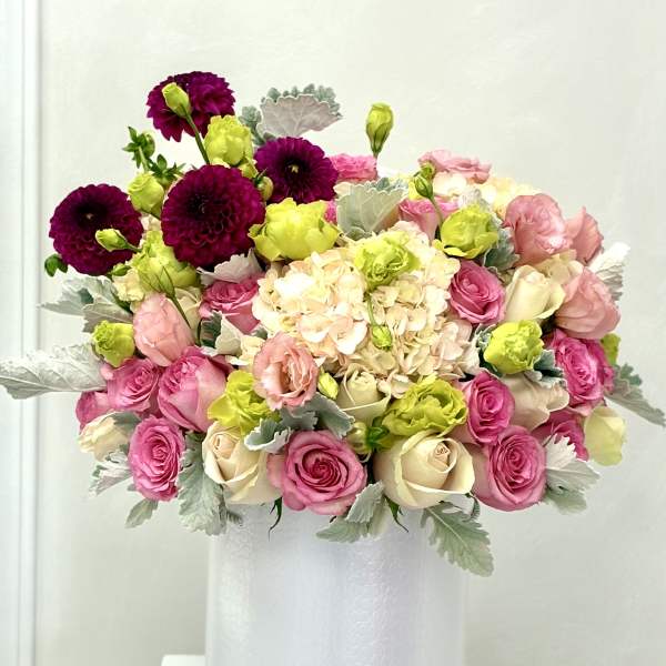 Pink and cream bouquet with lime accents in a white vase