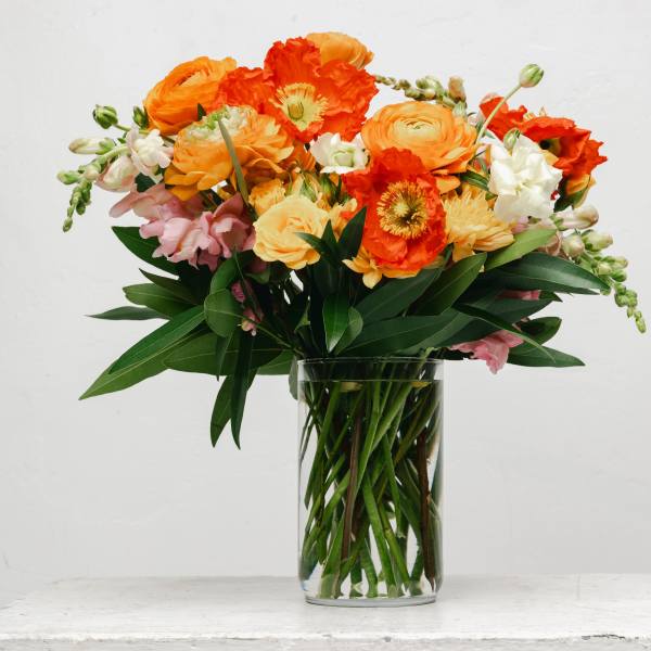 Orange and pink mixed bouquet in a clear glass vase