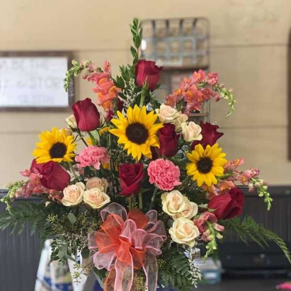 Mixed bouquet of sunflowers, roses, and carnations in a glass vase