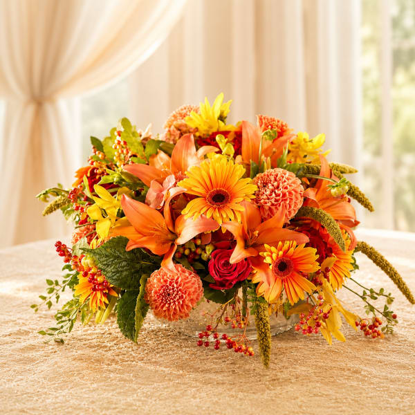 Orange and yellow floral arrangement in a clear glass bowl