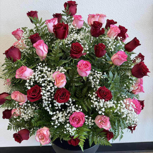 Large arrangement of red and pink roses in a black vase