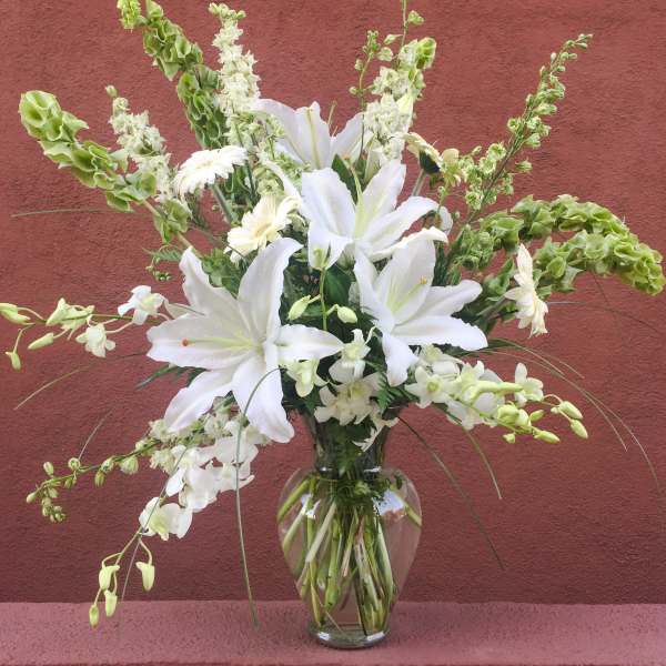 White lilies and orchids arranged in a clear glass vase