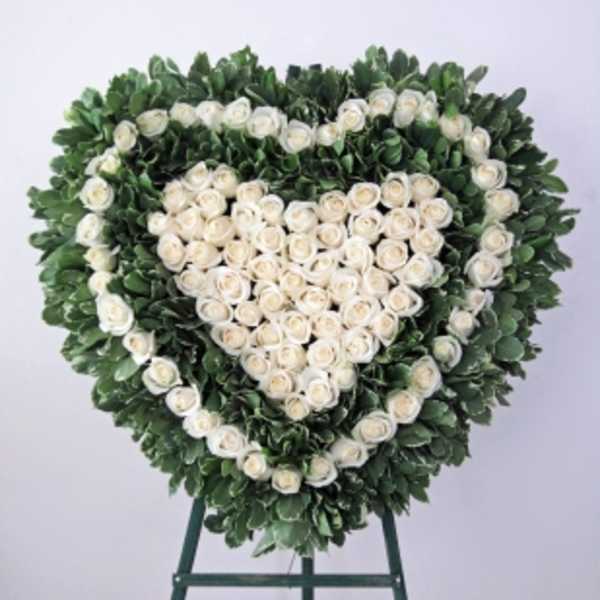 Heart-shaped floral wreath of white roses on a stand