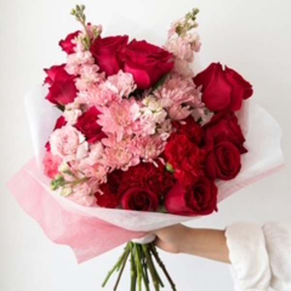 Bouquet of red roses and pale pink flowers wrapped in white and pink paper