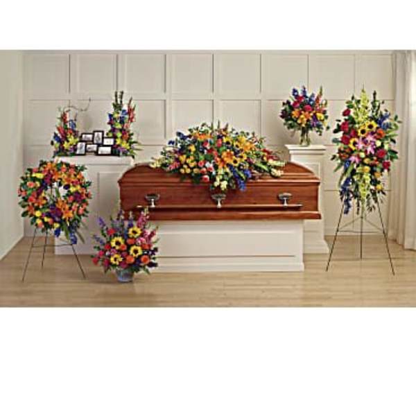Colorful funeral casket spray with standing floral tributes