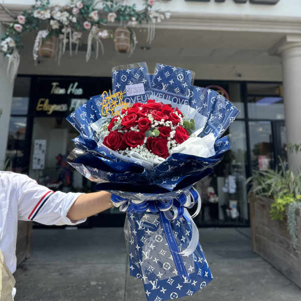 Bouquet of red roses wrapped in blue patterned paper with a ribbon