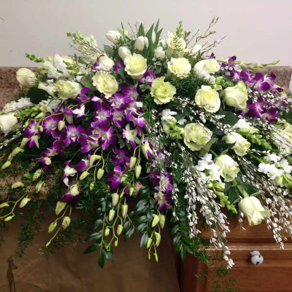 Large white and purple floral spray arranged over a casket