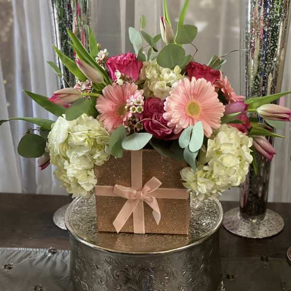 Pink and white floral arrangement in a glittery gift box with a ribbon