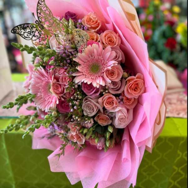 Pink bouquet of roses and gerbera daisies wrapped in pink paper