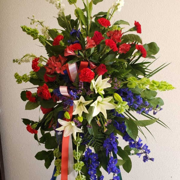 Tall standing floral spray with red, white, and blue flowers on a green easel