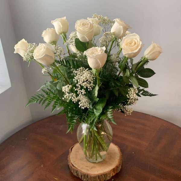 White roses arranged in a clear glass vase with baby's breath