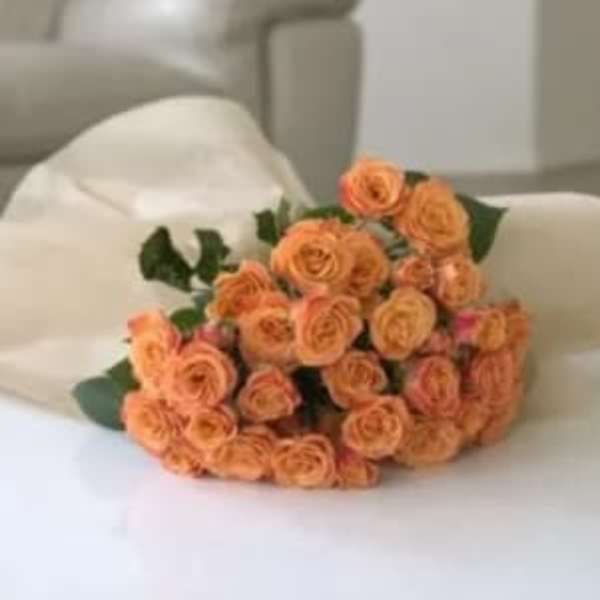 Bouquet of peach spray roses wrapped in white paper