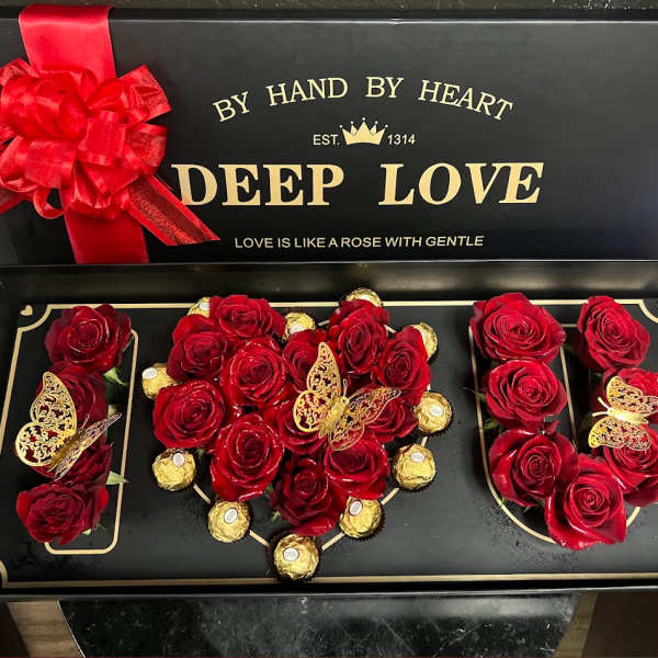 Red roses and gold-wrapped chocolates arranged in a gift box