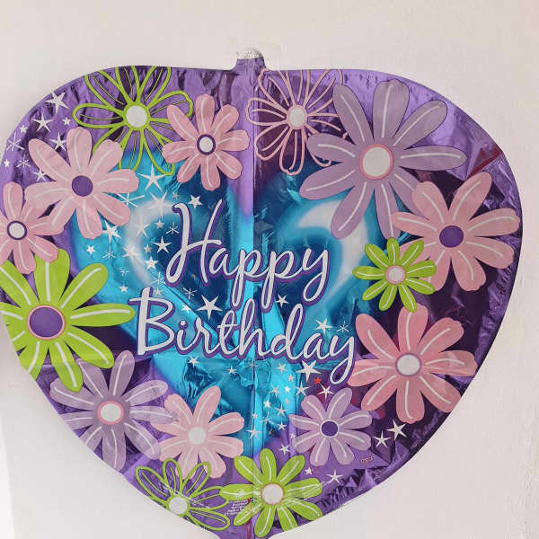 Heart-shaped birthday balloon with colorful daisy graphics