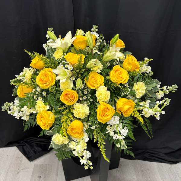Yellow roses and white lilies in a black pedestal arrangement
