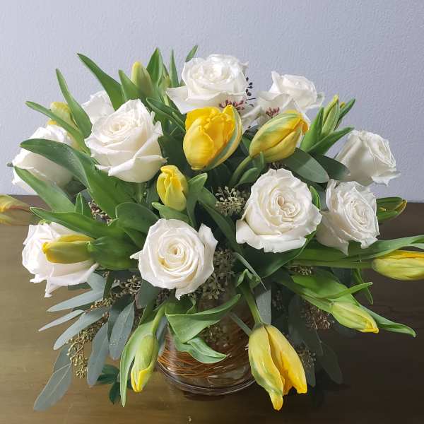 White roses and yellow tulips arranged in a glass bowl