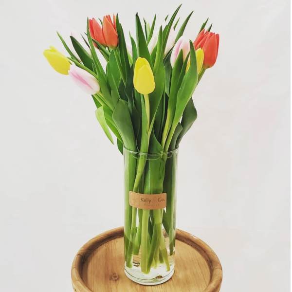 Glass vase of colorful tulips on a wooden stand