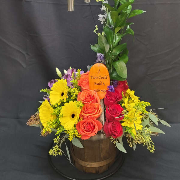 Colorful floral arrangement with wind chimes in a wooden basket