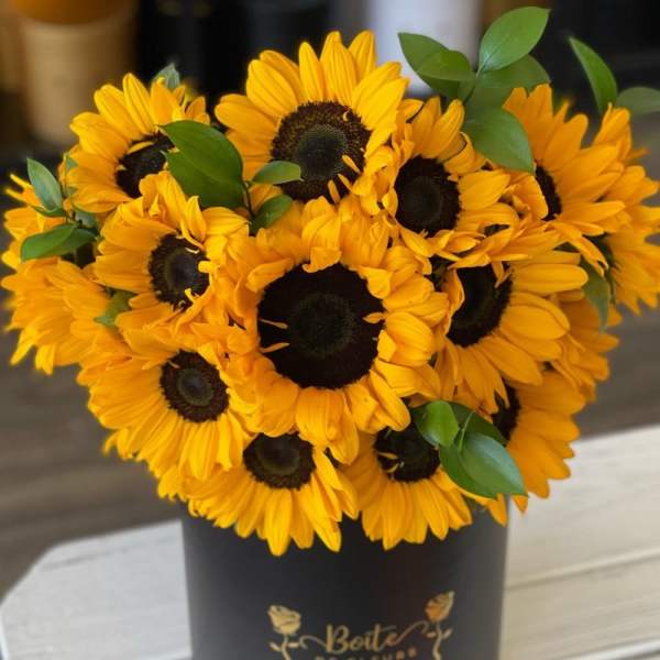 Bouquet of yellow sunflowers in a black hatbox