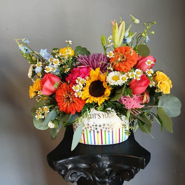 Colorful mixed flower arrangement in a striped gift box