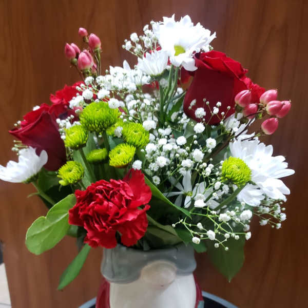 Bouquet of red roses, white daisies, and green button mums in a vase