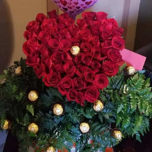 Heart-shaped red rose arrangement with a pink heart balloon