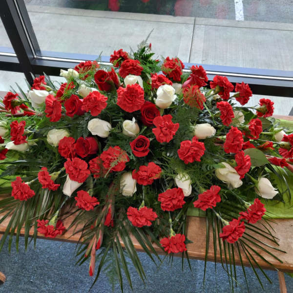 Large red and white floral casket spray on a table