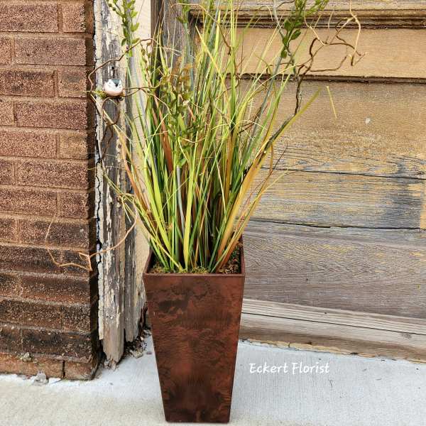 Tall potted arrangement of ornamental grasses in a copper planter