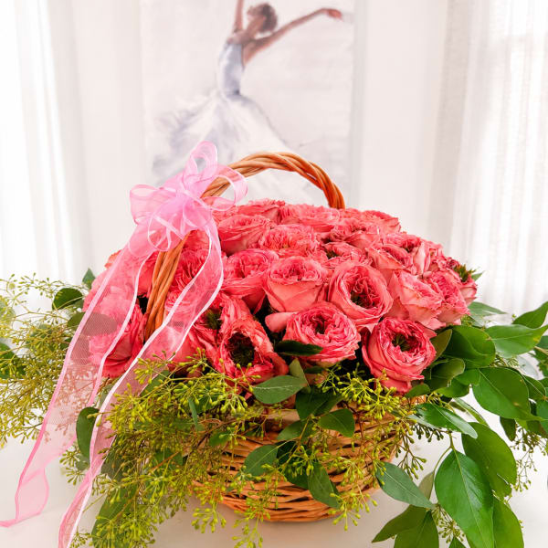 Pink roses in a wicker basket with a pink ribbon