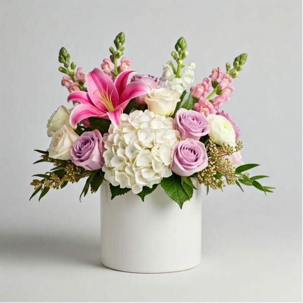 Pink lilies, roses, and white hydrangea in a white vase