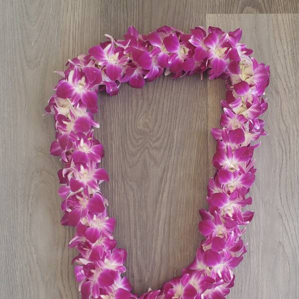 Pink orchid lei on a wood surface