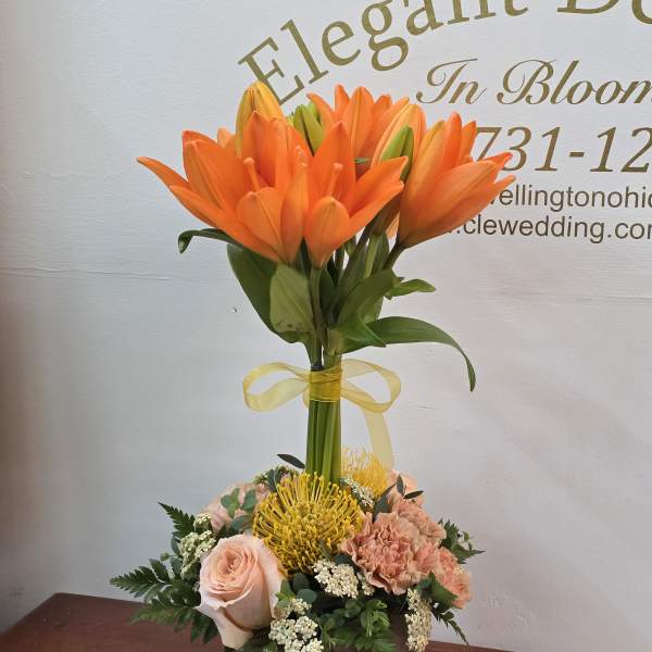 Orange lilies in a wooden box with peach roses and yellow pincushion blooms