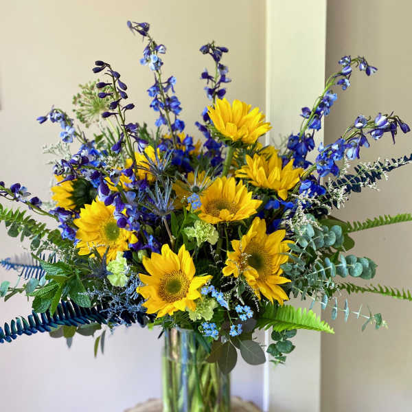 Bouquet of yellow sunflowers and blue flowers in a glass vase